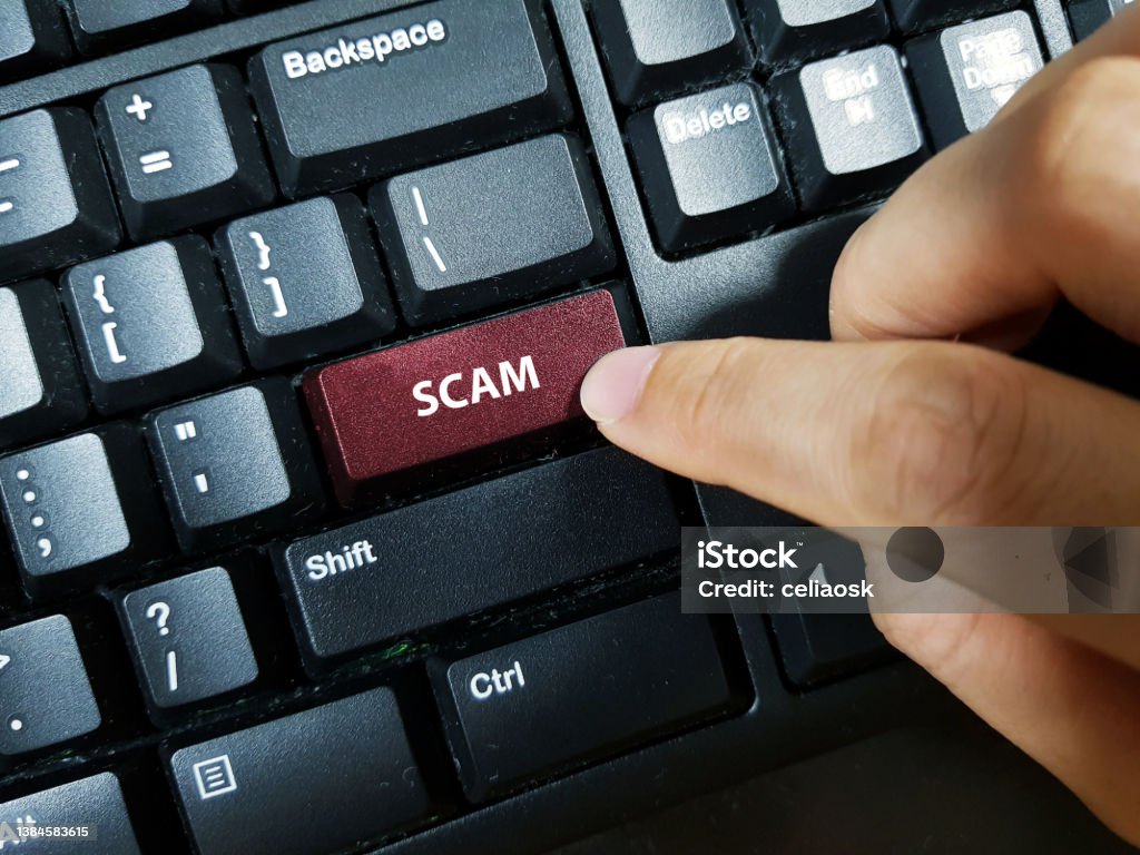A person pressing the keyboard key with the word "SCAM" Mail Stock Photo
