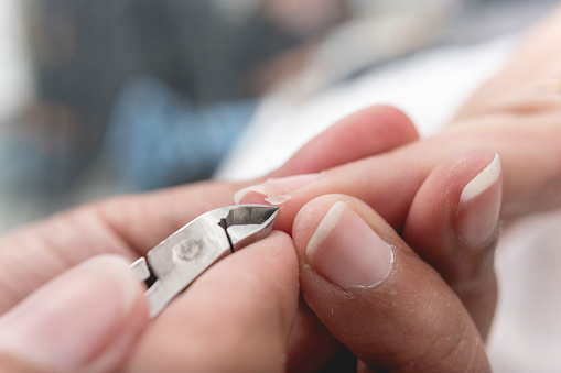 Un manicurista usa un par de pinzas para quitar una uña colgante del borde de una uña índice o perionychium. En un salón o spa de uñas. photo