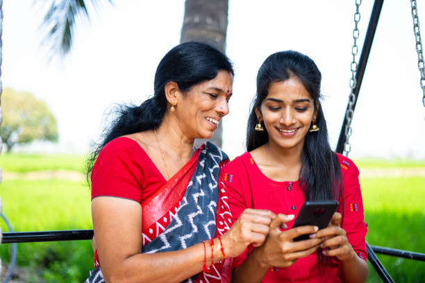 istock Relaxed mother and daughter on swing using mobile phone - concept of happiness, bonding, using social media and Indian family 1384585202