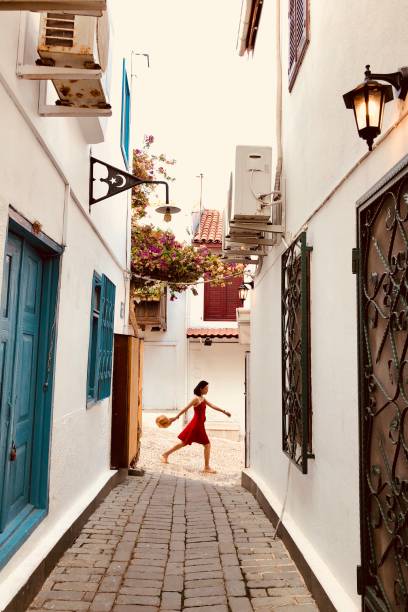 Beautiful and slim girl walking pass the small lane in an ancient town at Aegean Sea, Turkey stock photo
