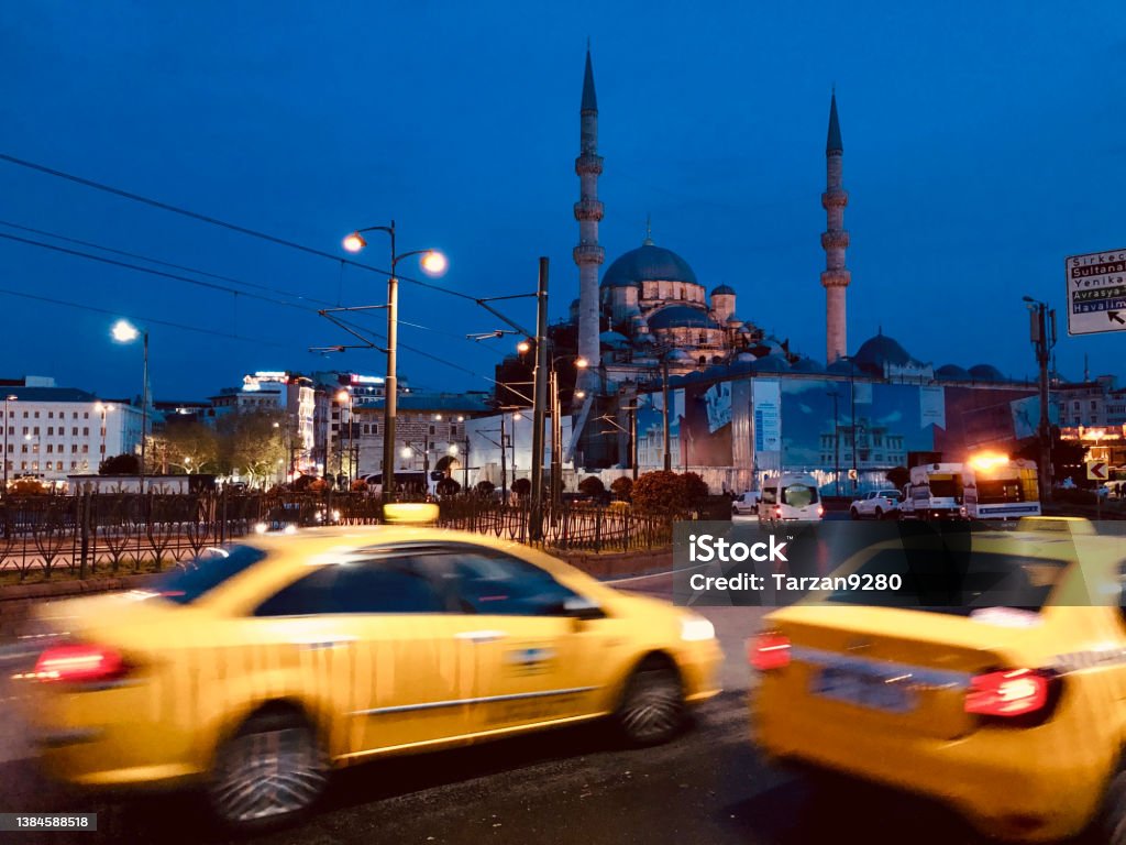 Yellow cabs on  Galata bridge and the Yeni Mosque, Istanbul, Turkey The yellow cabs and the blue tone perfectly contrast and match each other. Car Stock Photo