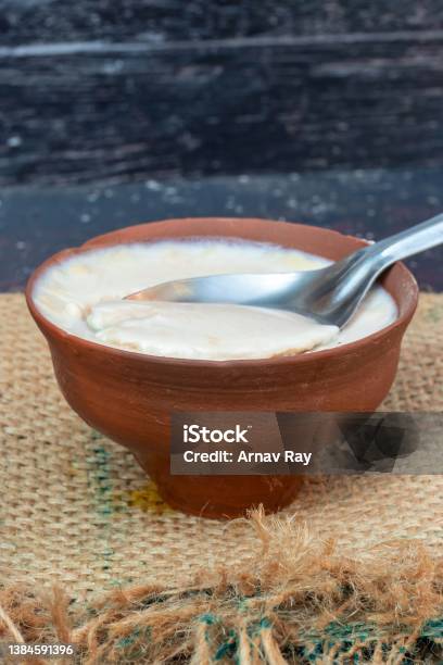 Closeup Of Homemade Dahi Or Curd In An Earthen Bowl With Spoon On Burlap Fabric In Vertical Orientation Stock Photo - Download Image Now