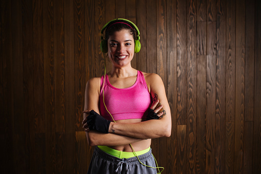 Young woman is smiling as she standing with crossed hands and headphones