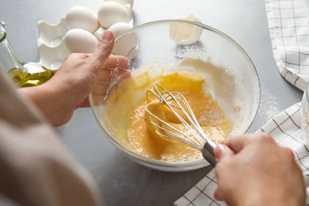 istock Woman whisking dough for cake at light grey table, closeup 1384600041