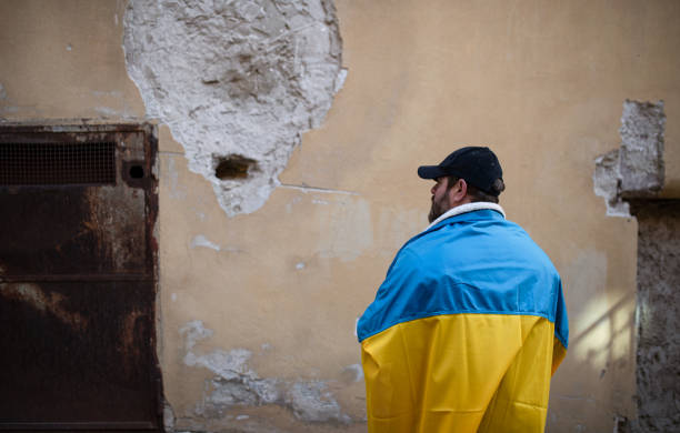 istock Protestor covered with blue and yellow Ukrainian flag protesting against war in Ukraine in street 1384602662