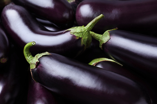 Stock photo showing close-up, elevated view of heap of elongated striped aubergines being sold in fruit and vegetable green grocer's section of supermarket, ready to eat for five a day healthy eating diet.