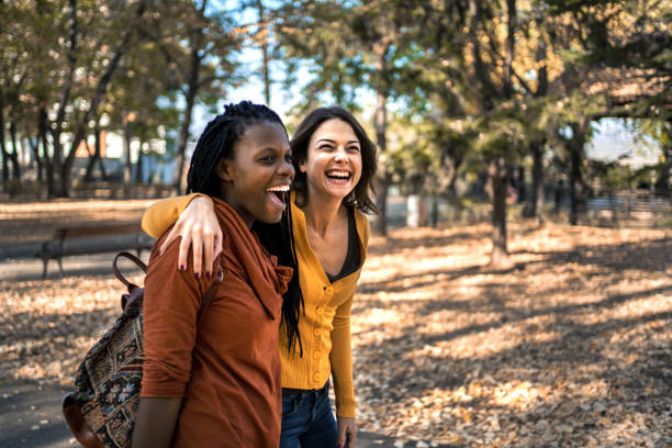 istock Two multiethnic friends walking through the park 1384608299