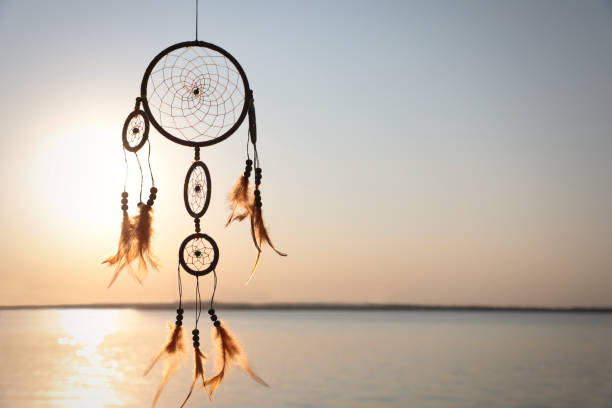 istock Beautiful handmade dream catcher near river at sunset. Space for text 1384610336