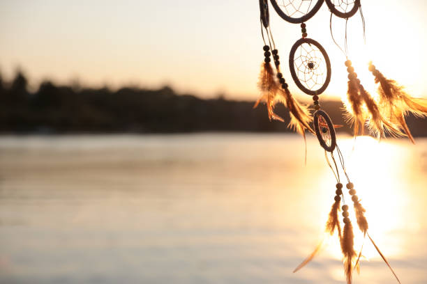 istock Beautiful handmade dream catcher near river on sunny day. Space for text 1384610369