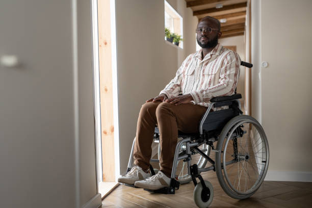 istock Young man with disability looking at camera while sitting in wheelchair 1384610411