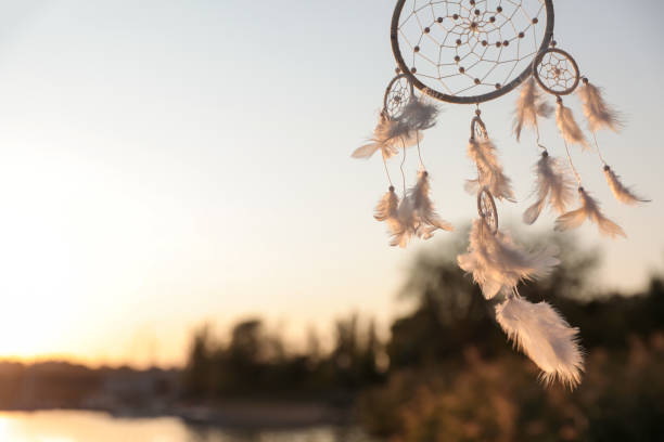 istock Beautiful handmade dream catcher near river on sunny day. Space for text 1384610426