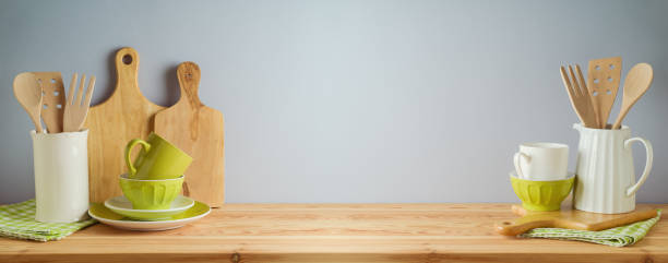 istock Kitchen utensils and green dishware on wooden table over gray background. Spring and Easter holiday mock up for design 1384610586