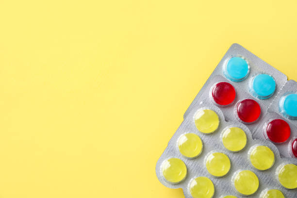 istock Cough drops in blisters on yellow background, top view. Space for text 1384610599