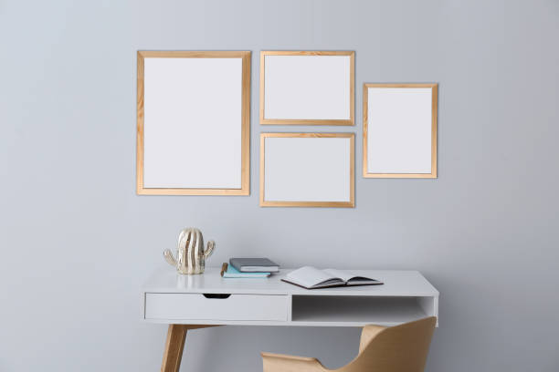 istock Table and chair near light grey wall with empty posters. Mockup for design 1384611634