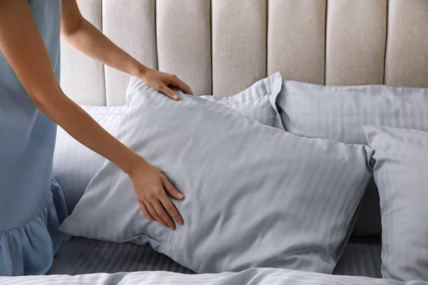 istock Woman putting soft pillow on bed, closeup 1384611759