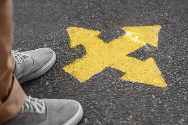 istock Man standing near arrow on asphalt, closeup 1384611928