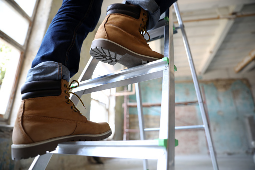 Professional constructor on ladder in old building, closeup