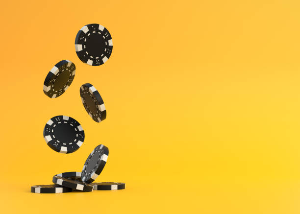 istock Lots of black poker chips falling down on a yellow background with copy space 1384613816