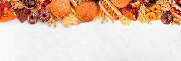 istock Junk food top border over a white marble banner background 1384617237