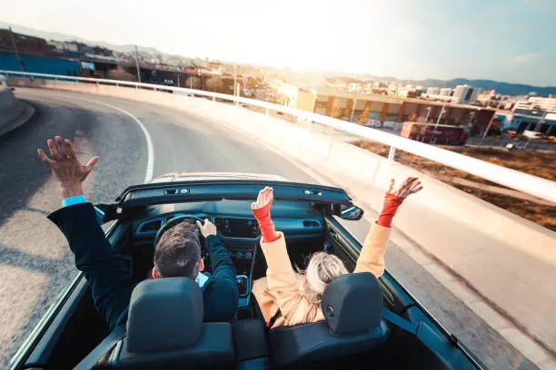 Happy couple driving on the road in convertible car - Friends rent cabrio auto on vacation - Roadtrip, freedom, travel and transport rental service concept