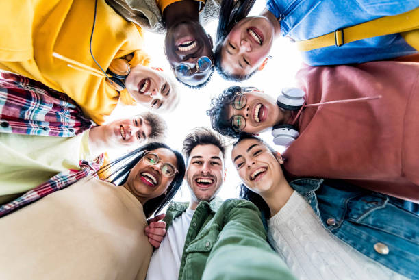 Multiracial group of young people standing in circle smiling at camera - International teamwork students hugging together - Human resources and youth culture concept Multiracial group of young people standing in circle smiling at camera - International teamwork students hugging together - Human resources and youth culture concept multi ethnic group college student group of people global communications stock pictures, royalty-free photos & images