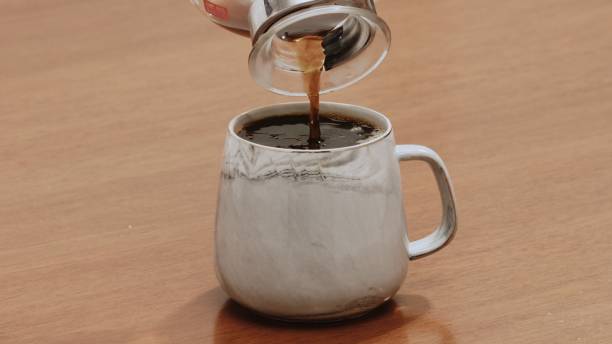 istock Black specialty coffee being served in mug on wooden table 1384620737