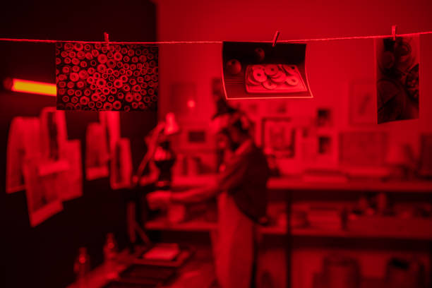 istock Row of several wet developed photos hanging on thread in dark laboratory 1384626242