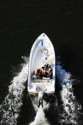 Sodertalje, Sweden - July 24, 2021: High angle view of an open tw seated small motorboat with two people on board travels at speed.