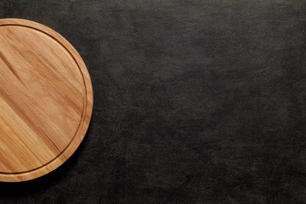 istock Cutting board round wooden on dark background, top view, space to copy text. 1384629459