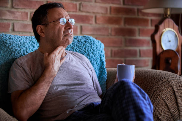 desespero homem idoso hispânico tendo uma caneca com chá para ajudar a aliviar a dor de garganta - tonsillite - fotografias e filmes do acervo