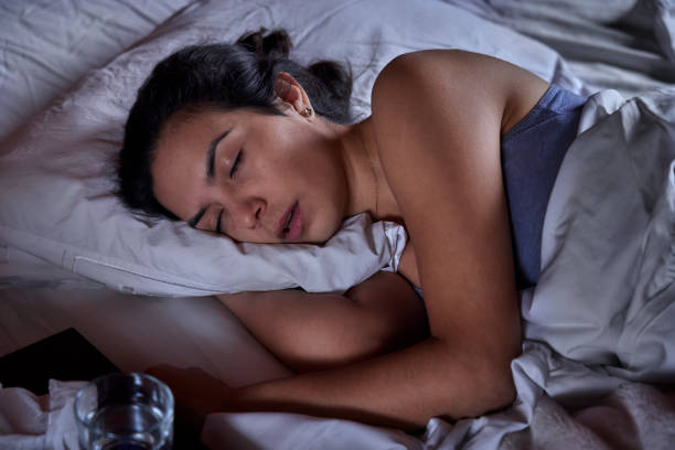 Hispanic young woman laying on bed with sore throat stock photo