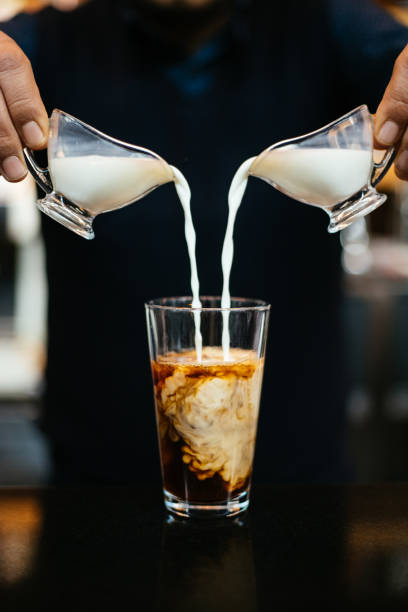 homme versant le lait dans le café glacé - milk shake coffee latté cold photos et images de collection