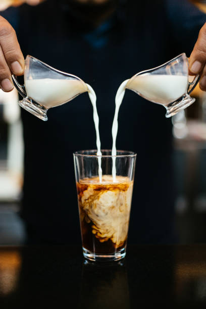 man pouring milk in iced coffee - caramel latté coffee cafe macchiato imagens e fotografias de stock