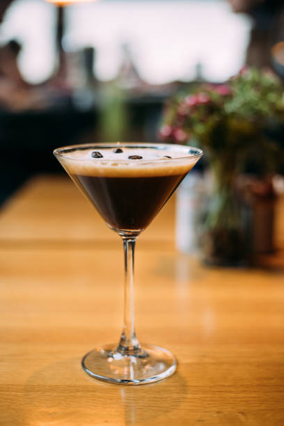 A glass of esspresso martini on wooden table Espresso martini coctail garnished with coffee beans on wooden table coffee liqueur stock pictures, royalty-free photos & images