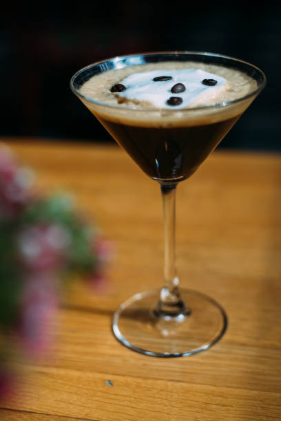 Espresso martini coctail garnished with coffee beans on wooden table Espresso martini coctail garnished with coffee beans on wooden table coffee liqueur stock pictures, royalty-free photos & images