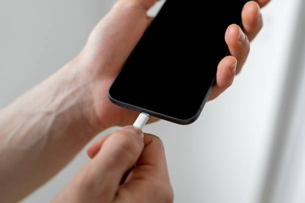 istock Man holding smart phone by connecting charger 1384640680