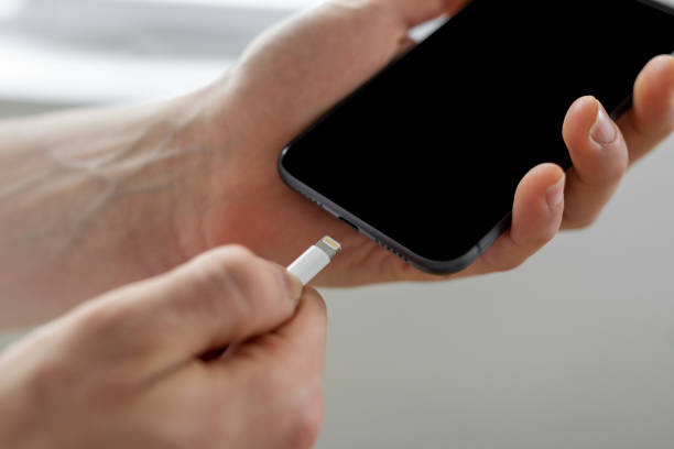 istock Man holding smart phone by connecting charger 1384640702