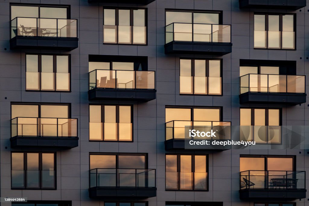 The evening sun is reflected in the modern glass facade with balconies Apartment Stock Photo
