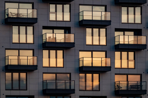 The evening sun is reflected in the modern glass facade with balconies stock photo
