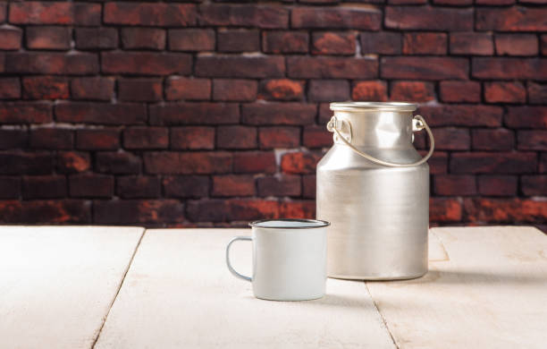 Milk jug and mug on a white wooden table, dark background, selective focus.