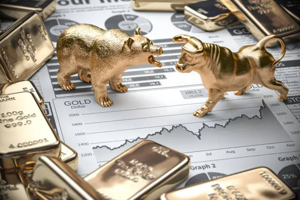 Photo of Golden bars and ingots of gold with bull and bear on stock chart. Investment and finance concept.