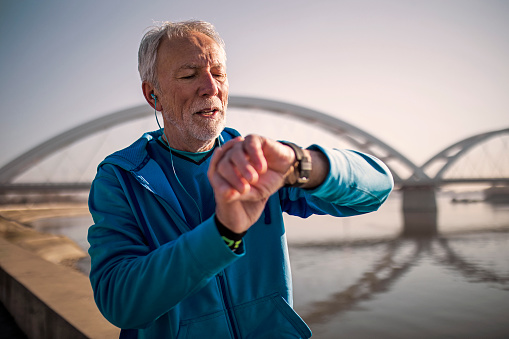 Senior Man on a bridge using Smart Watch