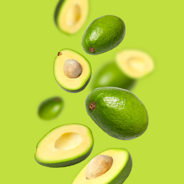 istock Creative layout with ripe flying avocado halves on green background. Healthy food, diet, tropical exotic fruit, trendy food product. Minimalistic summer food concept. Organic avocado. Pop art design 1384649708