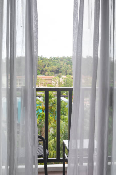 istock A window with a transparent tulle, access to a balcony overlooking palm trees in a tropical country. Travel and tourism 1384649797