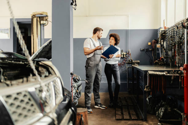 istock Mechanic With Clipboard and Customer at Workshop 1384650660