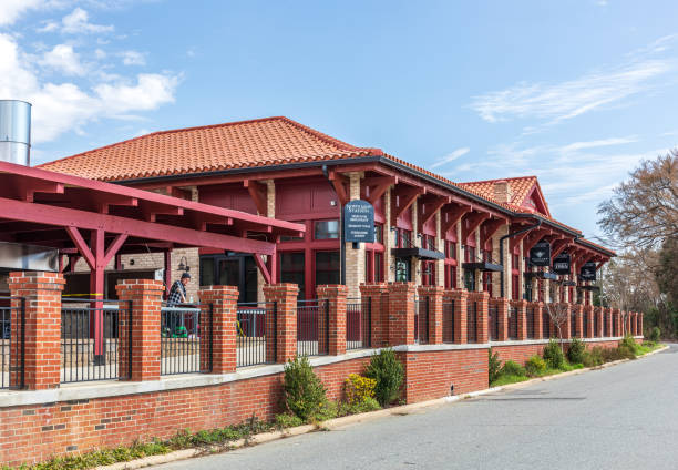 Belmont, NC, USA-8 March 2022: Old train depot, called North Main Station, converted to stores and restaurant. One man work at outdoor dining for the Heirloom Restaurant.
