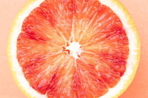 Single blood orange slice on orange background.