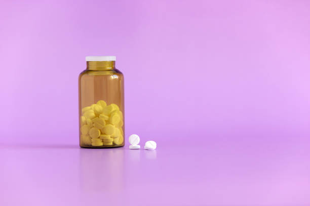 White pills, medical tablets, placebo or vitamins and brown bottle with medicine on purple background closed up, vertical plane, copy space on the write White pills, medical tablets, placebo or vitamins and brown bottle statin photos stock pictures, royalty-free photos & images