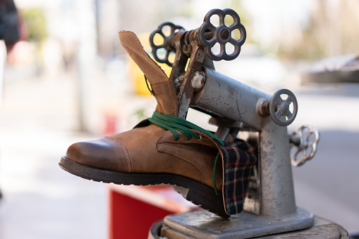 Close-up of professional shoe expander cobbler tool with old shoes in shoe maker store.
