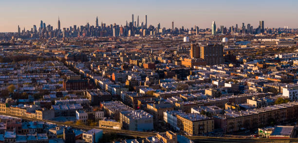 Manhattan Midtown Skyline includes the Empire State Building, Hudson Yards, and other iconic skyscrapers. View over the residential district of Bushwick, Brooklyn, at sunset.   Extra-large, high-resolution stitched panorama. Remote view of the Manhattan Skyline illuminated in the night over the residential district of Bushwick, Brooklyn, in the sunset. stitched image stock pictures, royalty-free photos & images